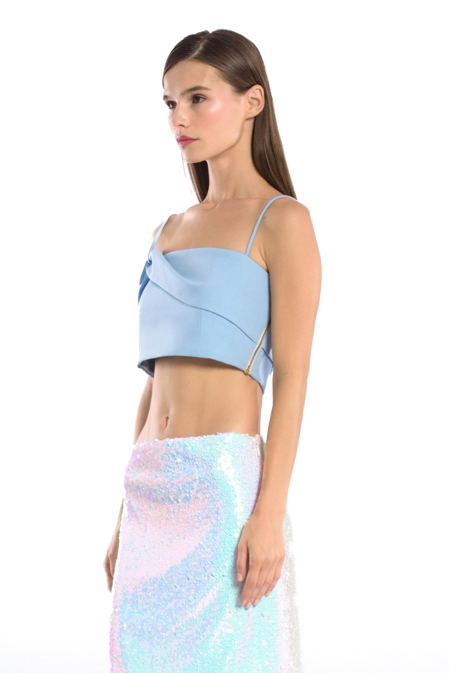 Model wearing asymmetric off shoulder crepe crop top in pastel blue color and iridescent sequins mini skirt